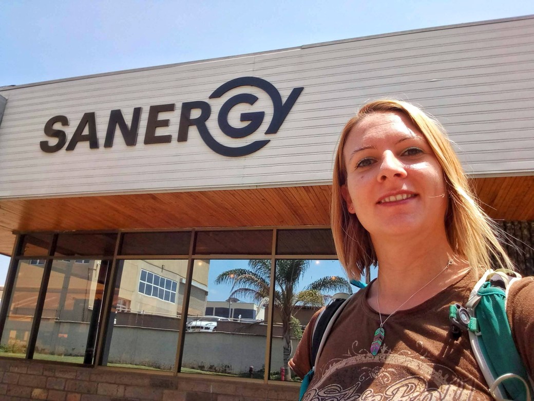 Me outside the Sanergy office with the logo in the background