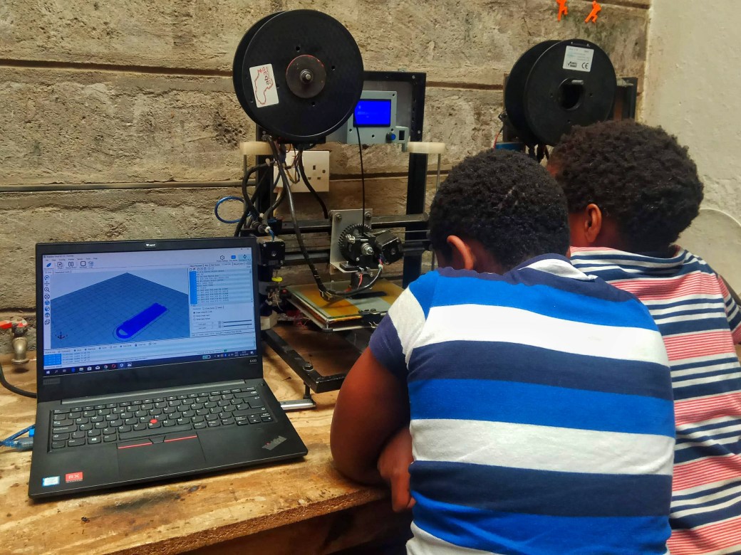 A pair of children watching a 3D printer in action