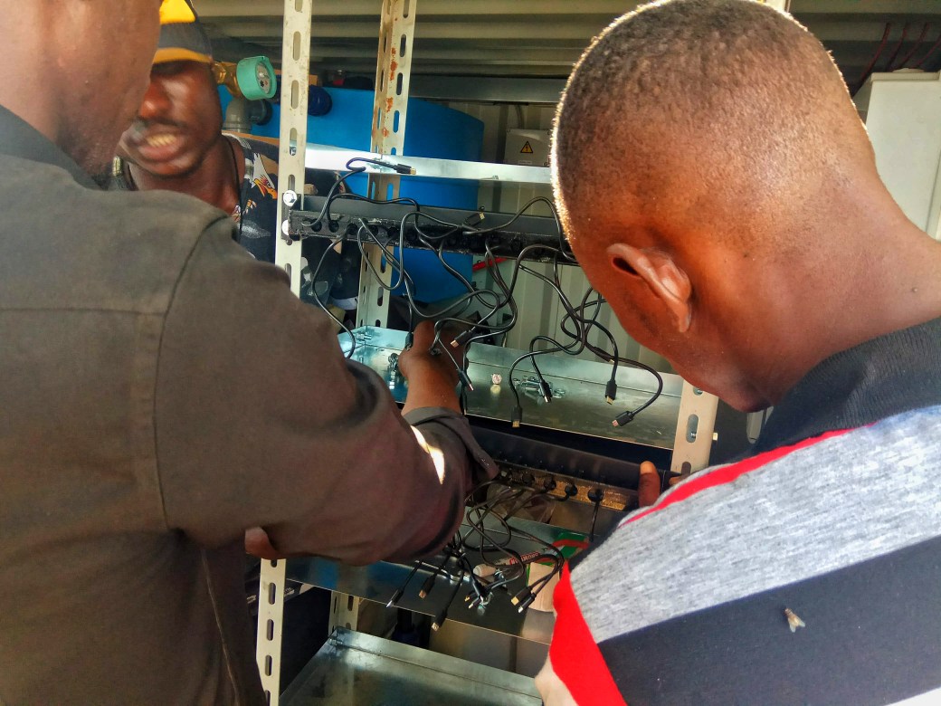 Two men installing charging cables to supply power to the community
